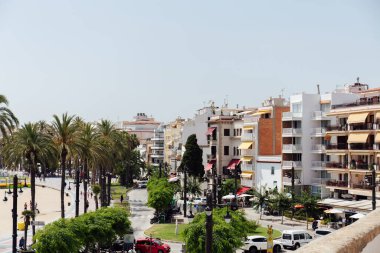 CATALONIA, SPAIN - 30 Nisan 2020: Arkaplanda binalar, palmiye ağaçları ve mavi gökyüzü bulunan şehir caddesi 