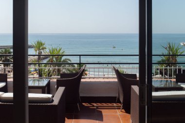 Katalonya, İspanya 'da deniz manzaralı ve palmiye ağaçlı terastaki sandalye ve masalar 
