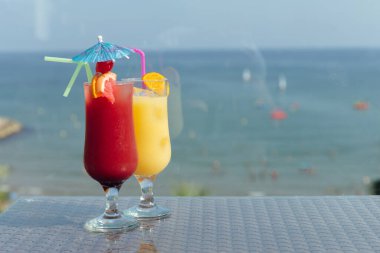 Glasses of cocktails on table with sea and blue sky at background  clipart