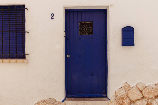 Blue mailbox and wooden door near number of house in Catalonia, Spain  