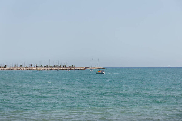 Яхты в море возле пирса с голубым небом на заднем плане в Каталонии, Испания
 