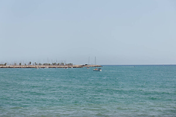 Яхты в море возле пирса с голубым небом на заднем плане в Каталонии, Испания
 