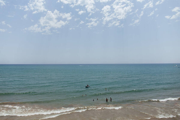 People swimming in sea near boat on coast of Catalonia, Spain 