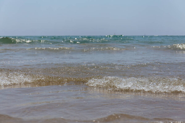 Selective focus of sea waves with blue sky at background in Catalonia, Spain 