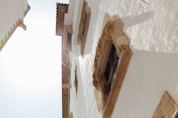 Low angle view of white facades of houses with sunlight and sky at background, Catalonia, Spain