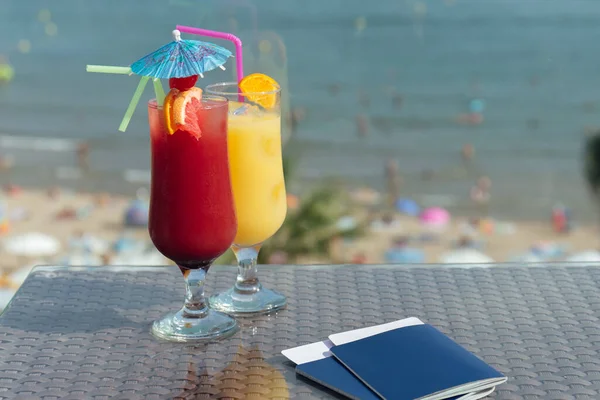 带着机票 背景为海滩的鸡尾酒和护照的玻璃杯 — 图库照片