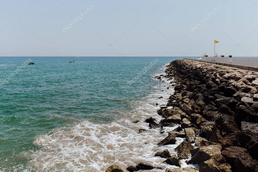 Paesaggio marino con pontile e pietre su un cielo limpido sullo sfondo in Catalogna, Spagna