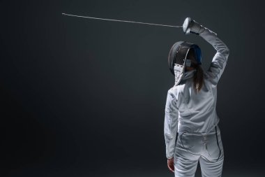 Back view of fencer holding rapier above head isolated on black 