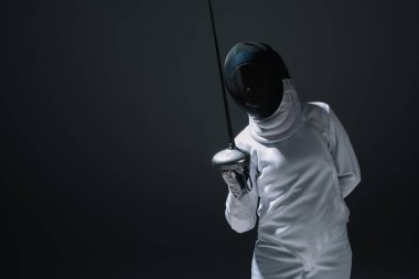 Kılıç ustası kadın eskrim kıyafeti ve maskeli Rapier 'ı siyah üzerinde tutuyor. 