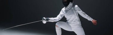 Horizontal image of fencer training with rapier on black background clipart
