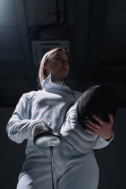 Güzel eskrimci, rapier ve eskrim maskesi tutuyor. 