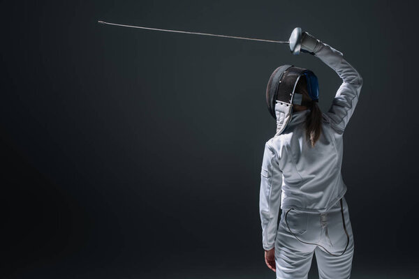 Задний вид фехтовальщика, держащего рапье над головой изолирован на черном
 