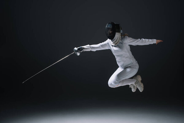 Fencer holding rapier while jumping isolated on black 