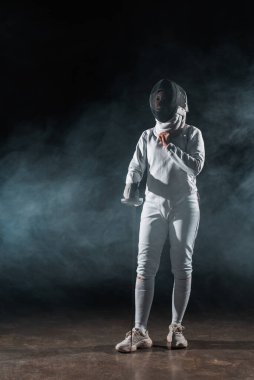 Fencer adjusting fencing mask on black background with smoke  clipart