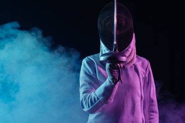 Kılıç ustası, eskrim maskeli kadın siyah arka planda dumanla rapier tutuyor. 
