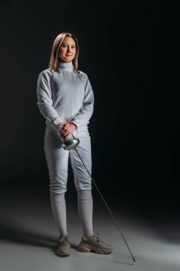 Eskrim takımındaki güzel eskrimci gri arka planda Rapier 'ı tutuyor.