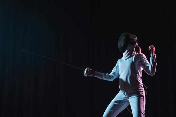 Swordswoman fencing with rapier isolated on black 