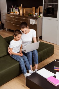 Anne ve oğlu evde online eğitim sırasında dizüstü bilgisayar kullanıyor. 