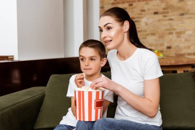 Anne ve oğlu evde film izlerken patlamış mısır yiyorlar. 