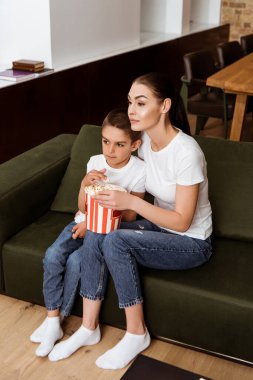 Anne ve çocuk evde kanepede film izlerken patlamış mısır yiyorlar. 