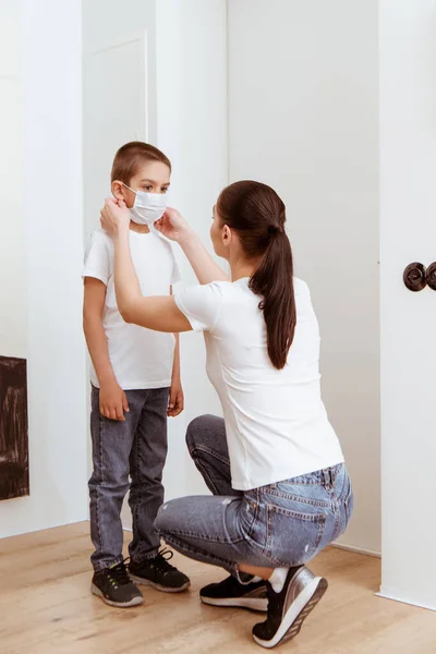 Mujer Poniendo Máscara Niño Cerca Puerta Pasillo — Foto de Stock