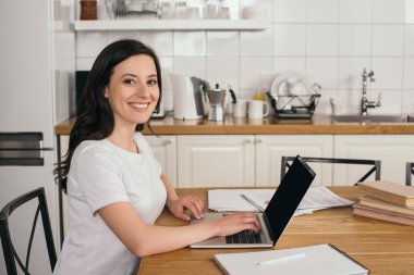 Evde boş ekranlı dizüstü bilgisayar kullanan neşeli kız, online çalışma konsepti