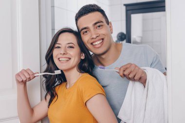 Banyoda diş fırçası tutan mutlu çok ırklı çift. 