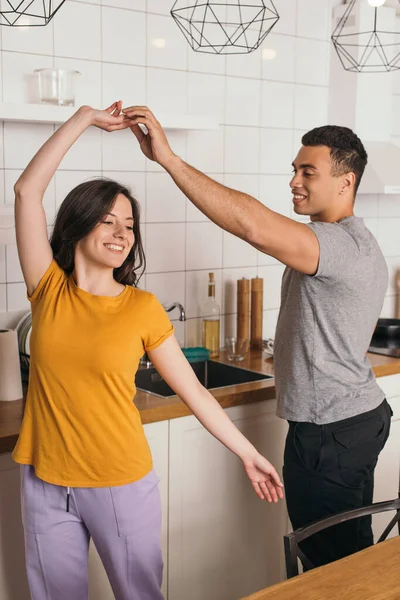 快乐的跨种族夫妇在厨房里跳舞 — 图库照片