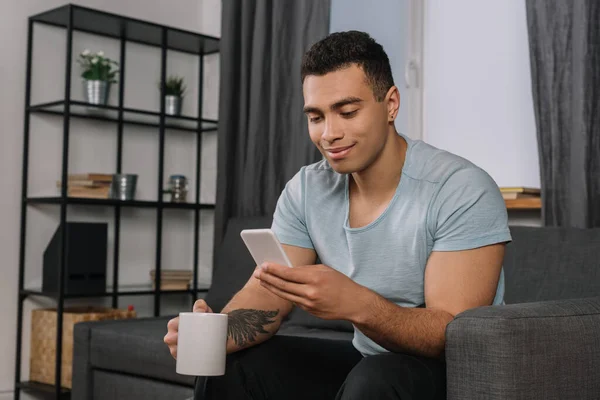 Happy Mixed Race Man Tattoo Holding Cup Using Smartphone — Stock Photo, Image