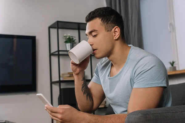 Handsome Mixed Race Man Tattoo Drinking Coffee Using Smartphone — Stock Photo, Image
