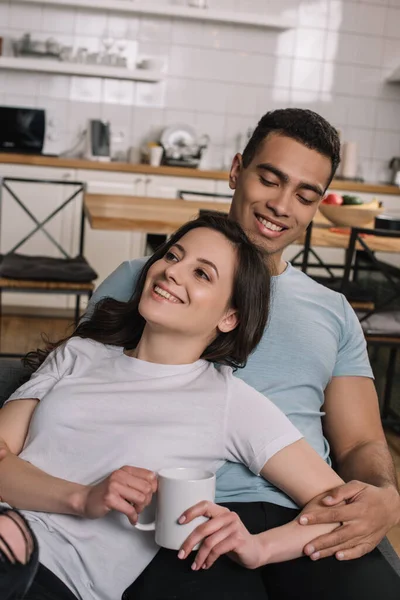 Vrolijk Meisje Holding Kopje Koffie Buurt Gemengd Ras Vriendje Woonkamer — Stockfoto