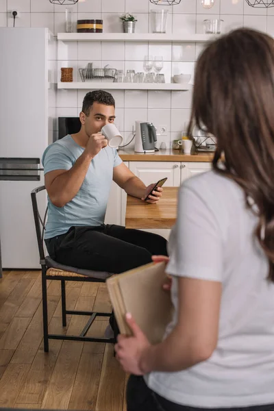 Selective Focus Mixed Race Man Drinking Coffee Looking Woman Book — Stock Photo, Image