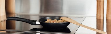 Panoramic crop of noodles in frying pan on stove in kitchen  clipart