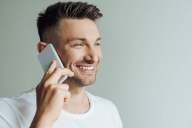 Akıllı telefonda konuşurken gülümseyen yakışıklı adam gride izole edilmiş. 