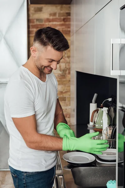 Sorrindo Homem Usando Luvas Borracha Perto Placas Brancas Cozinha — Fotografia de Stock