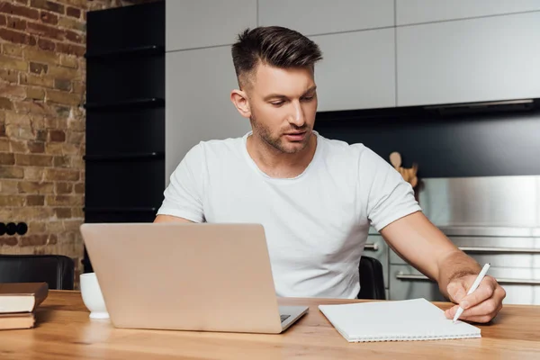 Hombre Guapo Celebración Pluma Cerca Portátil Portátil Mientras Que Estudio — Foto de Stock