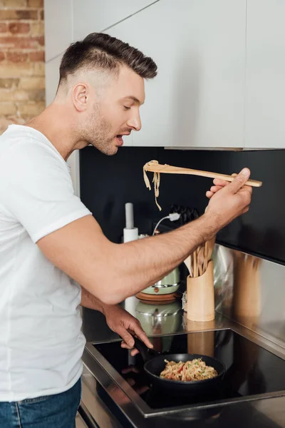 Side View Handsome Man Holding Wooden Spatula While Cooking Noodles — Stock Photo, Image