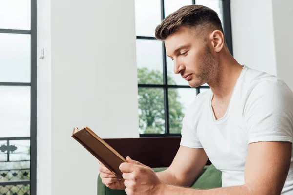 Άνθρωπος Διαβάζει Βιβλίο Ενώ Κάθεται Στον Καναπέ Στο Σαλόνι — Φωτογραφία Αρχείου