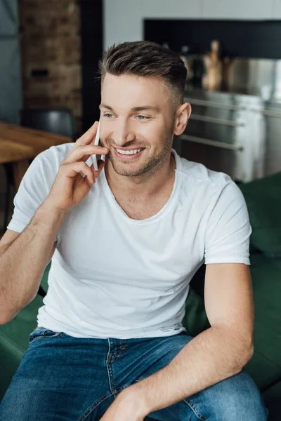 Hombre Guapo Sonriendo Mientras Habla Teléfono Inteligente Casa — Foto de Stock