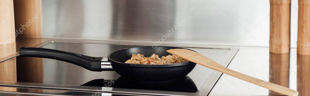 Panoramic crop of noodles in frying pan on stove in kitchen 