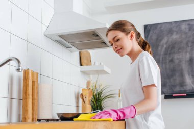 Pembe lastik eldivenli mutlu kadının seçici odak noktası mutfak temizliği. 