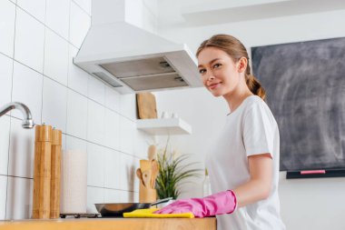 Pembe lastik eldivenli neşeli kadının seçici odak noktası mutfak temizliği. 