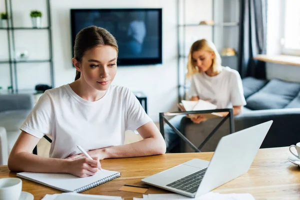 Enfoque Selectivo Mujer Mirando Computadora Portátil Mientras Escribe Cuaderno Cerca —  Fotos de Stock