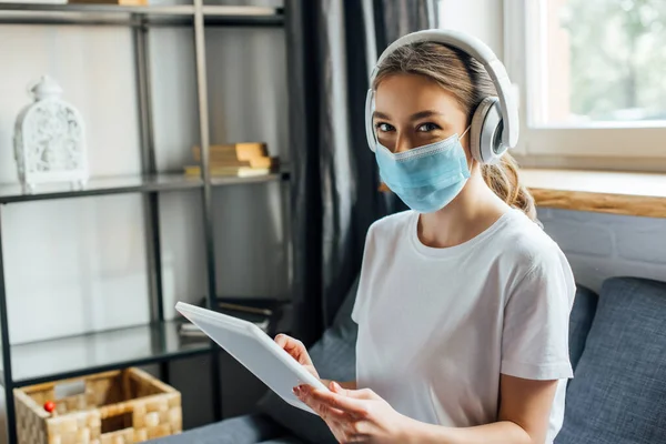 Femme Masque Médical Écouteurs Utilisant Une Tablette Numérique Sur Canapé — Photo