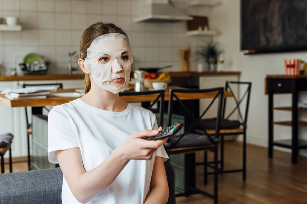 Jonge Vrouw Het Gezicht Masker Houden Afstandsbediening Thuis — Stockfoto