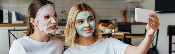 Hermanas Mascarillas Tomando Selfie Con Teléfono Inteligente Casa Tiro Panorámico —  Fotos de Stock