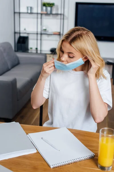 Selective Focus Blonde Woman Putting Medical Mask Papers Notebook Glass — Stock Photo, Image
