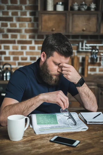 Uomo stanco con giornale sul tavolo — Foto stock