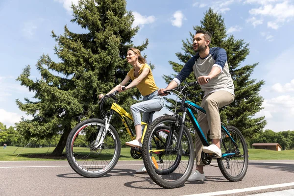 Couple chevauchant sur des vélos dans le parc — Photo de stock