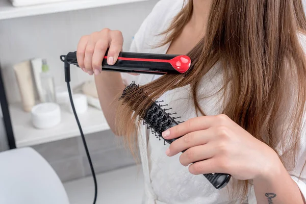 Frau benutzt Haarglätter — Stockfoto